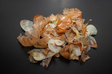 Onion peel isolated on black table.Close up of scattered dry onion peel as background.Close up view...