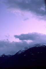Sunset over the alpine mountains with snowy peaks and dramatic cloud formation