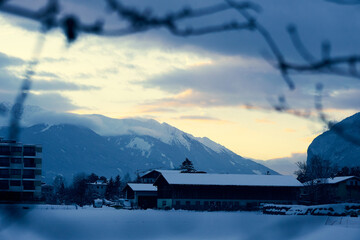 Winter landscape featuring snowy mountains and a barn in the Alps during twilight