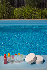 Poolside scene with chlorine tablets, water test kit, and reagent bottles used for testing and...