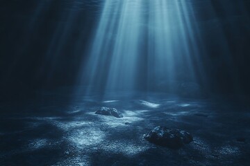 Deep ocean floor with sunbeams penetrating dark blue water illuminating rocks and sandy seabed underwater