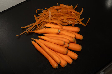 Carrot waste and peeled carrots on black table.View of pile of various organic waste after cooking...