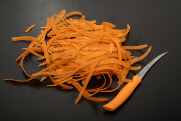 Carrot waste on black table and vegetable peeler.View of pile of various organic waste after...