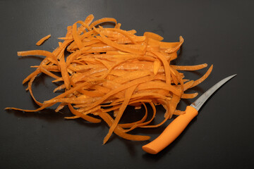 Carrot waste on black table and vegetable peeler.View of pile of various organic waste after...