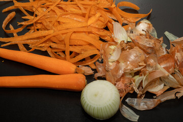 Onion peel and carrot waste on black table and vegetable peeling knife.View of pile of various...