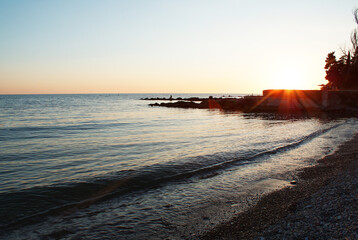 Sunset over sea, sun glare on water and clouds, background