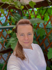 portrait of a mature woman in a summer gazebo with a vine background
