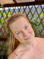 portrait of a mature woman in a summer gazebo with a vine background
