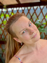 portrait of a mature woman in a summer gazebo with a vine background