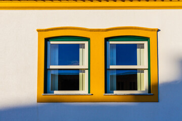 A brightly colored yellow and green window frame with two modern windows