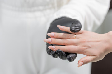 Close-up of perfect nude manicure with almond-shaped nails in light beige gel polish, salon scene