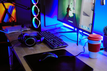 Gaming setup with large monitor displaying video game, mechanical keyboard, gaming mouse, headset...