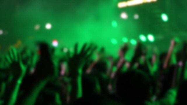 Bokeh view of people dancing on the dance floor during a concert at a festival. Blurred background footage. Concept of crowd enjoying rock and roll, live dj set, hip hop rap party, night club event.