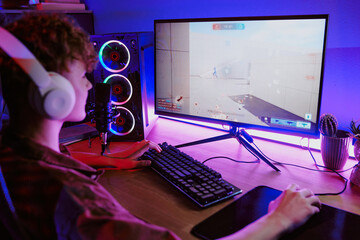 Caucasian teenage boy wearing headphones live streaming video game at home, sitting at desk with...