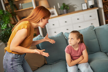 In a warm living room, a mother expresses her anger towards her daughter, who sits quietly with her...
