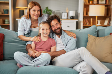 Obraz premium A family of three relaxes on a comfortable sofa, sharing laughter and joyful moments in their cozy living room. The atmosphere is warm, inviting, and filled with love.