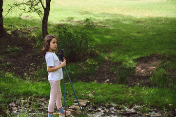 Young Girl Exploring Nature with Poles in Scenic Countryside Setting