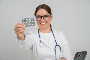A female doctor sits at a table and recommends pills. 