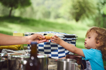 Parent Sharing Food with Toddler During Picnic Outdoors