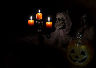 Skeleton with Candles and Pumpkin Lantern in Dark Halloween Scene
