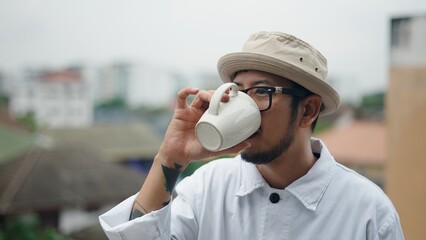 Young chef enjoying a coffee break on a rooftop, savoring the moment and urban view