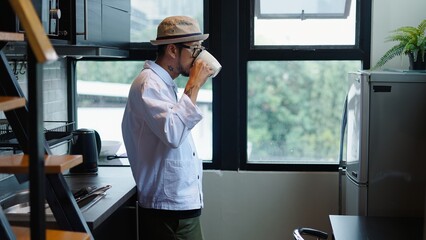Stylish man enjoying a cup of coffee in his modern, minimalist kitchen