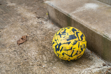 Yellow and black football next to concrete stair outdoors.