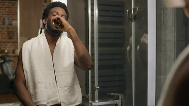 African American funny happy man singing in hairbrush home bathroom bake naked guy looking mirror morning shower ethnic male relaxing dancing sing song having fun healthy guy listen music hair care