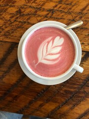 Flat lay shot of a Beet Latte with a leaf design in a white cup and saucer