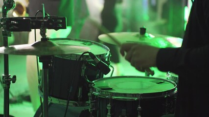 Close-up of hands of drummer, musician playing drums, hitting cymbals, drums with drumsticks. Drummer sets tempo of musical composition, performance of rock band, cover band, music festival, party.