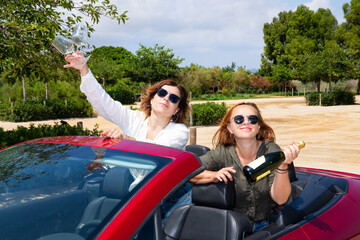Girlfriends in a red convertible celebrate summer and freedom