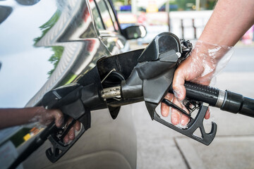Man driver hand refilling the car with fuel at the gas petrol station. 