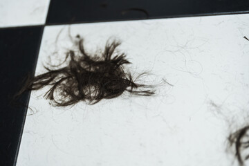 Hair remnants scattered on a contrasting tiled floor after a haircut