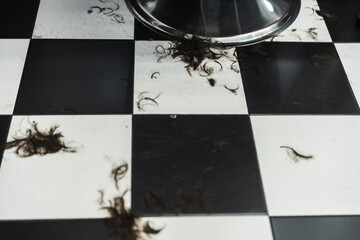 Hair trimmings scattered on black and white checkered flooring in barbershop
