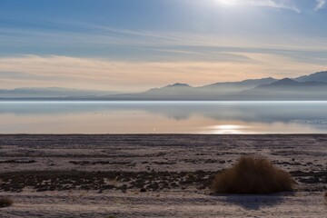 Sunrise over the Salton Sea in California, USA. The sun reflects off the calm water, with mountains...