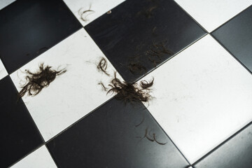 Clumps of hair scattered on a black and white tiled floor in a salon