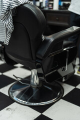 Classic black barber chair set against a checkered floor in a stylish barbershop