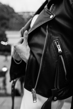 Black and white portrait of a smiling bride wearing a leather jacket and holding flowers, captured in a candid outdoor moment.  Smiling Bride in Leather Jacket &mdash; Black and White Portrait
