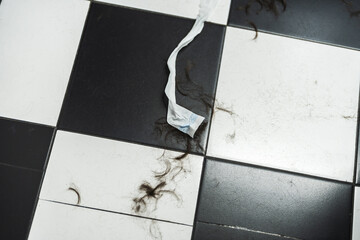 Hair and debris scattered on a stylish black and white tiled floor