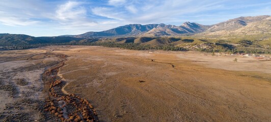 Aerial view of a vast, dry meadow in Thomas Mountain, Mountain Center, California, USA, framed by...