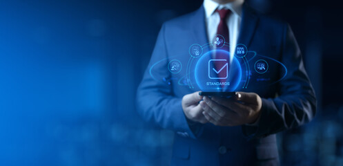 Businessman Holding smartphone with Standards Icons on Screen. Quality Management concept