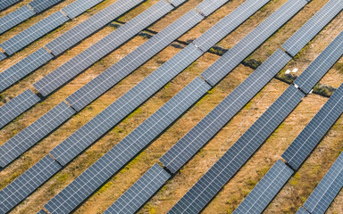 Aerial view of solar panels arranged in rows on dry grass field