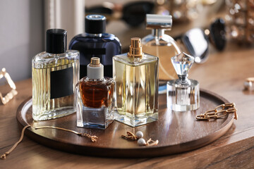 Bottles of different perfumes and accessories on wooden table, closeup
