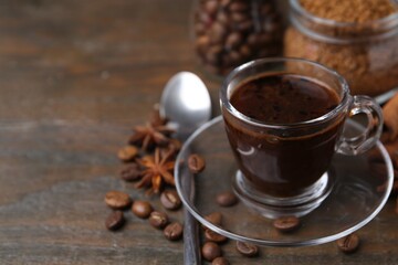 Cup of aromatic coffee, beans, instant powder and spices on wooden table, closeup. Space for text