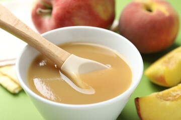 Baby food. Tasty puree in bowl and ingredients on green background, closeup