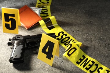 Forensic expert. Yellow crime scene tape, gun, passport and money on grey table, closeup. Space for...