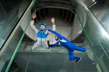 A male instructor teaches a woman how to fly in a wind tunnel. Free fall simulator.