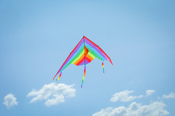 Colorful kite flying in blue sky, low angle view