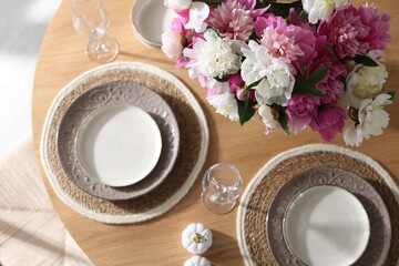 Beautiful table setting with bouquet of peonies indoors, top view