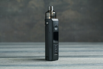 One electronic smoking device on wooden table against grey background, closeup
